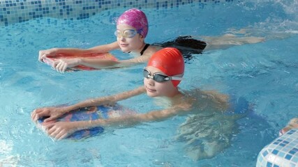 Three children learn to swim and dive in the pool together with a coach. Group of children on a swimming class.