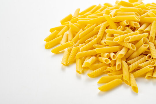 Raw dry penne pasta on white background.
Italian food penne pasta image for background.
