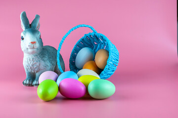 a rabbit and an inverted basket with easter eggs on a pink background copyscape