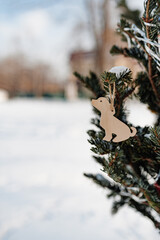 decor wood Christmas tree toy in shape of large dog made of wood on Christmas tree outside, snow....