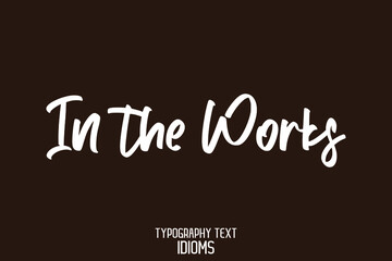 In the Works idiom Cursive Text Lettering Phrase on Brown Background