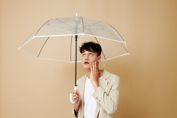 a man with an open umbrella in a jacket protection from the rain beige background