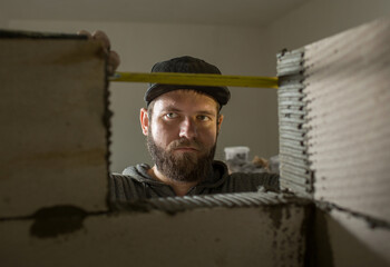 a man sits with a construction tape measure in his hands, and measures the future doorway. the process of laying a foam concrete wall indoors.