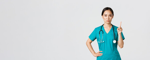 Covid-19, healthcare workers, pandemic concept. Serious-looking professional female asian doctor in...