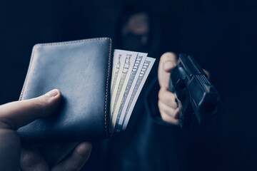 Man's hand holds out wallet of money to robber with gun. Armed robbery. Assault on unarmed man. Hundred and fifty dollars in open purse. Firearm is pointed at camera.