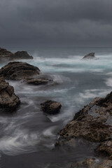 Ocean water flowing between rocks on the stormy day.