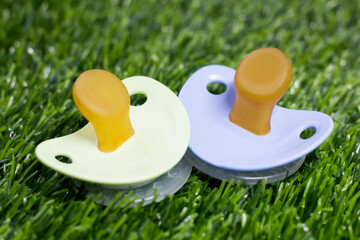 Two baby pacifiers on the grass