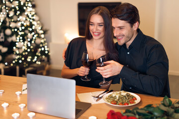 Couple having videocall using laptop drinking wine