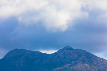 Fototapeta premium Panoramic view of impressive rock formations in the Mediterranean landscape of the Bavella mountains. Many dark rain clouds hang over the mountain peak. Corsica, France. Place for text.