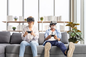 Obraz premium senior couple playing game and having fun together with virtual reality headset on the sofa