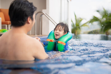 Fototapeta na wymiar Asian father and son having fun together in swimming pool