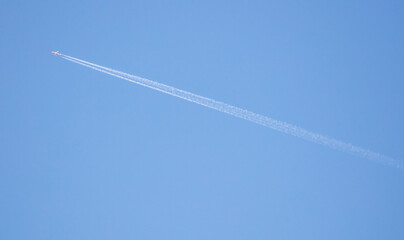 The trail from the plane against the blue sky.
