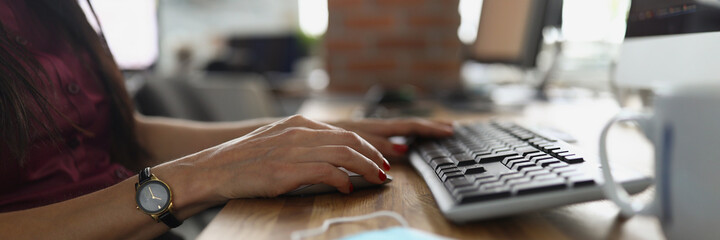 Female hands with a clock press the keyboard