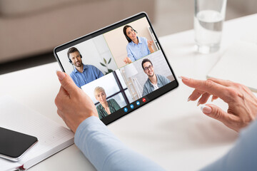 Woman Using Digital Tablet For Video Conference With Group Of Business People