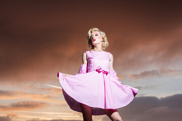 Woman in monroe dress on dramatic sky. Beautiful girl in stylish fashion clothes in summer. Fashion...