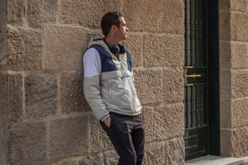 man with headphones leaning on the wall