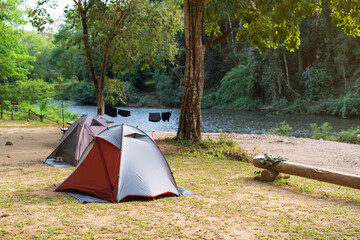 tourist camping tent and cabin campsite or campground near water on river stream and morning in...