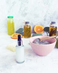 Blue clay, citruses, cream, herbal tinctures and aromatic oils in bottles, eucalyptus leaves on a light background, spa, natural ingredients