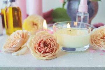 Spa, fresh pink roses, burning candles, oils and tinctures on a light background, healthy lifestyle, relaxation, home cosmetics, aromatherapy, romantic mood, alternative medicine