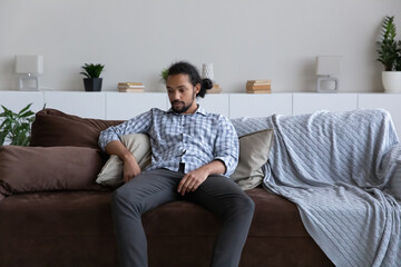 Passive bored sad African guy feeling tired, suffering from apathy, depression, sitting on sofa at...