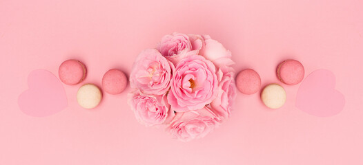 Flowers roses and sweets macaroons on pink background. Valentines day concept. Flat lay, top view, copy space.