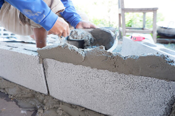 bricklayer building a wall with cement plaster, construction work.