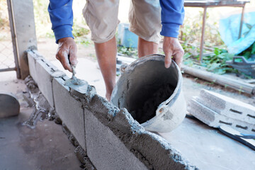 bricklayer building a wall with cement plaster, construction work.