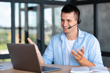 Fototapeta premium Happy caucasian employee call center, businessman, customer support manager wearing with headset using laptop computer for virtual meeting consulting client at on video call