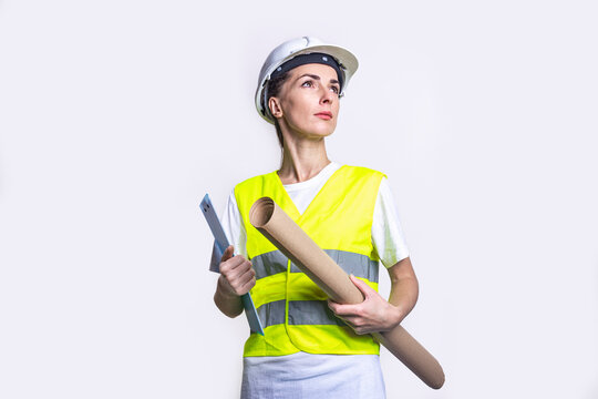 Young woman in building clothes holds a clipboard and craft paper on a light background.