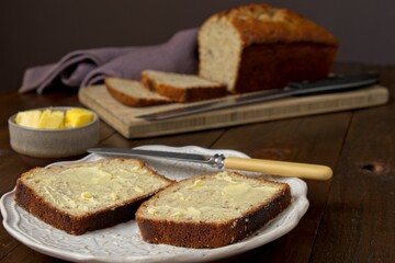 Fresh banana bread with buttered slices on plate