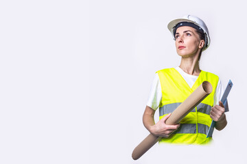 Young woman in building clothes holds a clipboard and craft paper on a light background.