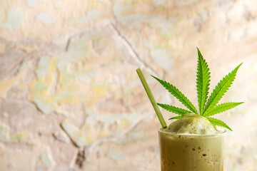 Close up photo of cannabis smoothie over abstract colorful wall in warm light background. Copy...