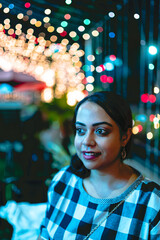 An Indian girl smiles as colourful blue light falls on her face. A girl smiles with excitement in an market decorated with lights to celebrate the festival of Diwali in India.