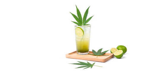 Photo of a glass of cannabis lemon soda with cannabis leaves and lemon in wooden tray isolated over white background. Copy space for text backdrop artwork. Eatable vegetable healthy concept ideas
