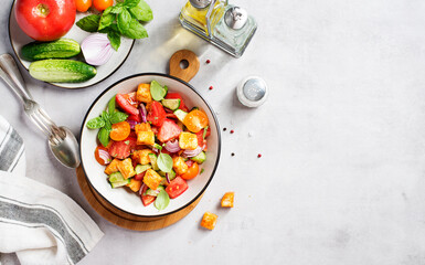 Tuscan Panzanella, traditional Italian salad with tomatoes and toasted bread. Vegetarian panzanella salad. Light gray background. Top view	