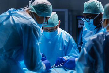 Multiracial team of professional medical surgeons performs the surgical operation in a modern...