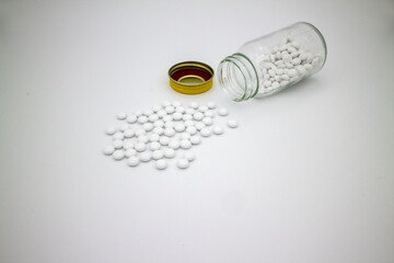 薬瓶からこぼれた白い錠剤、白背景 1
White tablets, medicaments, pills spread from...