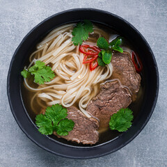 Pho Bo Soup with beef in bowl on gray stone table. Close up. Vietnamese cuisine.
