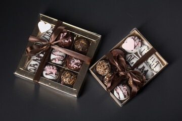 Candies in chocolate glaze. In a gift box. Tied with a ribbon tied into a bow. On a black background.