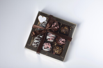 Candies in chocolate glaze. In a gift box. Tied with a ribbon tied into a bow. On white background.