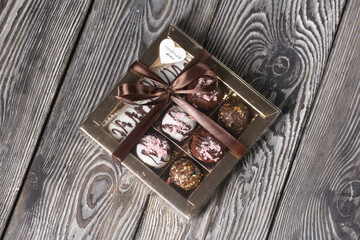 Candies in chocolate glaze. In a gift box. Tied with a ribbon tied into a bow. On pine boards.