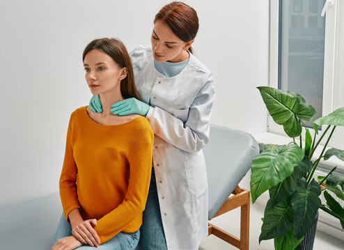 Doctor palpates of woman's neck for diagnostics of thyroid diseases and hypothyroidism at medical clinic. Thyroid treatment