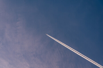 A plane in a blue sky with a white stripe.