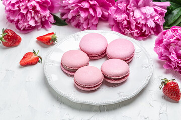 Obraz na płótnie Canvas pink macaron or macaroon cakes with peony rose on a white background. Banner, flyer, beautiful postcard, top view