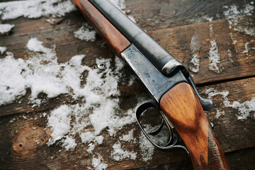 Beautiful vintage double-barreled shotgun made of wood on a background of snow