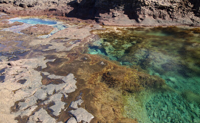 Fototapeta na wymiar Gran Canaria, calm natural seawater pools under the steep cliffs of the north coast and separated from the ocean by volcanic rocks, Sardina del Norte area in Galdar municipality 
