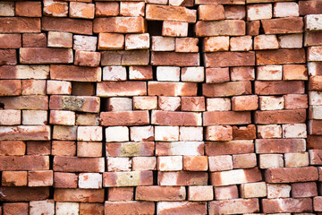 A high wall of loosely stacked red bricks