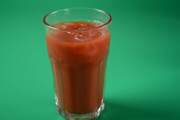 Full glass of fresh tomato juice with cherry tomatoes around . Very tasty and healthy tomato juice with ice cubes