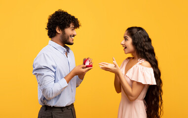 Passionate indian man proposing to his beloved lady, giving her engagement ring on Valentine's Day,...