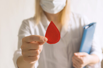 Concept of give blood donation, blood transfusion. Doctor in white coat holds drop of blood on...